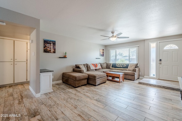 living area with light wood-type flooring, a textured ceiling, and ceiling fan