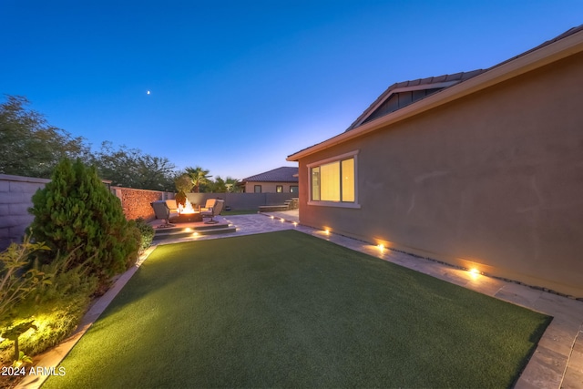 yard at dusk with an outdoor living space and a patio area