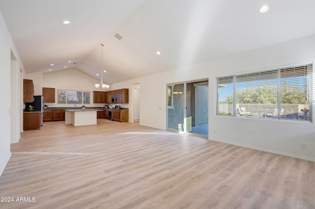 interior space featuring decorative light fixtures, a center island, a notable chandelier, and light hardwood / wood-style flooring