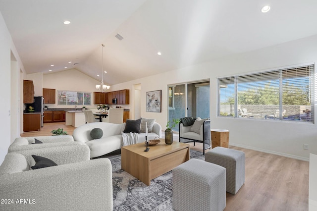 living room featuring light wood-type flooring, an inviting chandelier, and vaulted ceiling