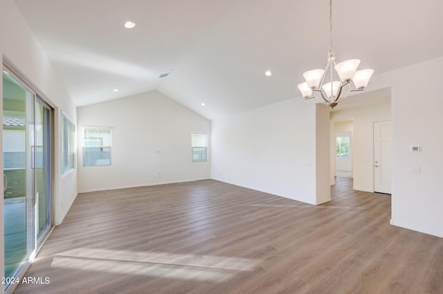 unfurnished room featuring lofted ceiling, wood-type flooring, and a notable chandelier