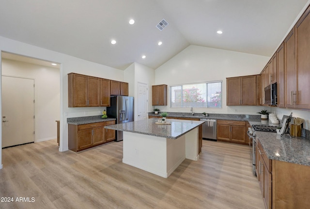 kitchen featuring high vaulted ceiling, light hardwood / wood-style flooring, stainless steel appliances, a center island, and stone countertops