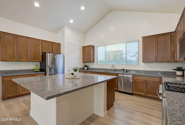 kitchen featuring a center island, stainless steel appliances, high vaulted ceiling, and light wood-type flooring