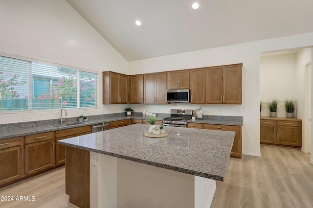 kitchen featuring light wood-type flooring, stainless steel appliances, sink, high vaulted ceiling, and a kitchen island