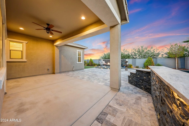 patio terrace at dusk featuring exterior kitchen and ceiling fan