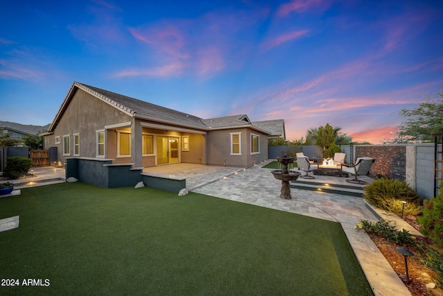 back house at dusk with an outdoor living space, a patio area, and a yard