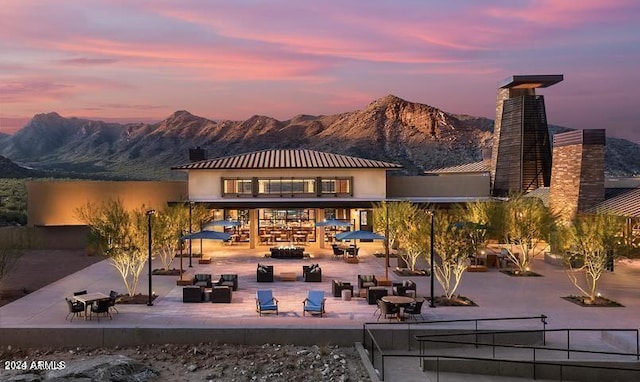 back house at dusk featuring a fire pit, a mountain view, and a patio