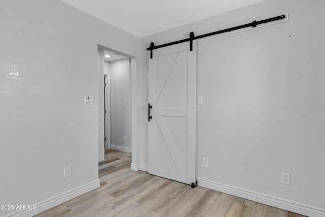 spare room featuring a barn door and light hardwood / wood-style flooring