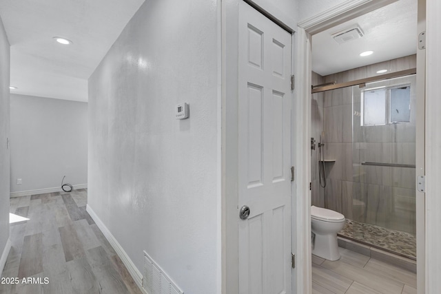 bathroom with an enclosed shower, wood-type flooring, and toilet