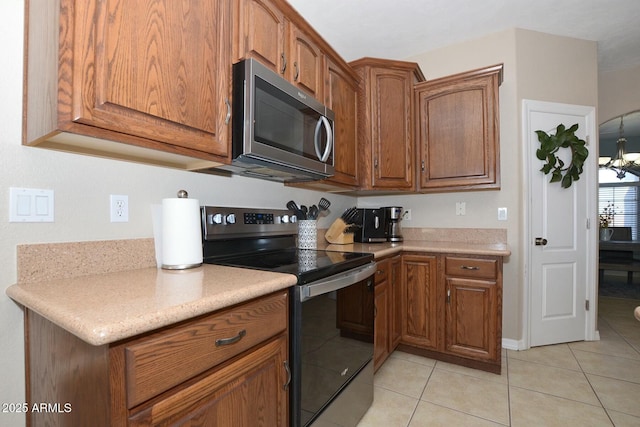 kitchen featuring light tile patterned floors, stainless steel appliances, and a notable chandelier