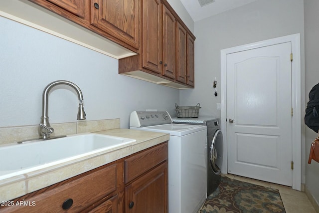 laundry room featuring washer and clothes dryer, cabinets, sink, and dark tile patterned flooring