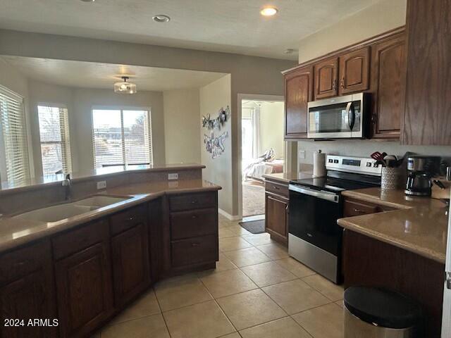 kitchen with dark brown cabinets, light tile patterned floors, sink, and appliances with stainless steel finishes