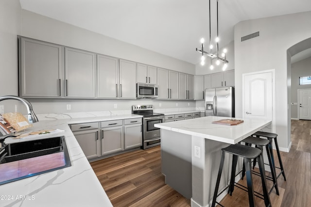 kitchen featuring dark wood-type flooring, hanging light fixtures, a kitchen island, and stainless steel appliances