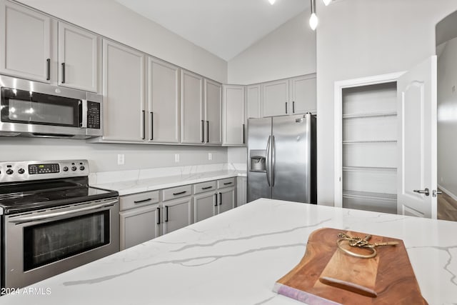 kitchen featuring gray cabinetry, light stone countertops, appliances with stainless steel finishes, and vaulted ceiling