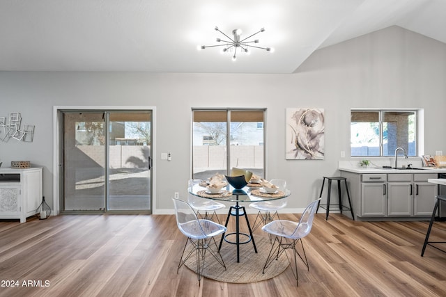 dining room featuring light hardwood / wood-style flooring, a wealth of natural light, lofted ceiling, and sink