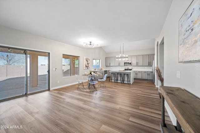 unfurnished living room featuring light hardwood / wood-style floors, lofted ceiling, and an inviting chandelier