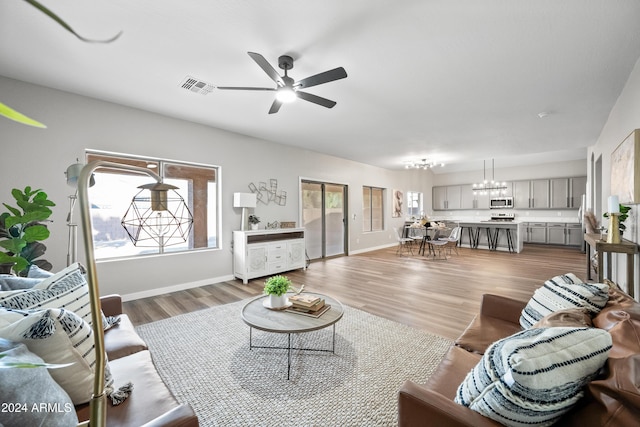 living room featuring hardwood / wood-style floors and ceiling fan with notable chandelier