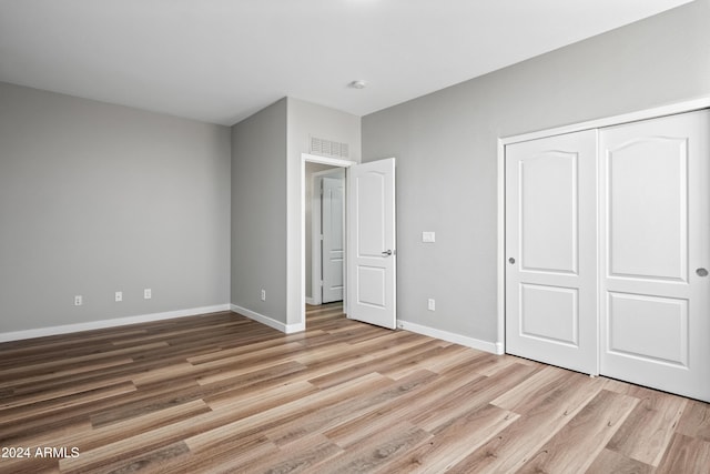 unfurnished bedroom with light hardwood / wood-style flooring and a closet