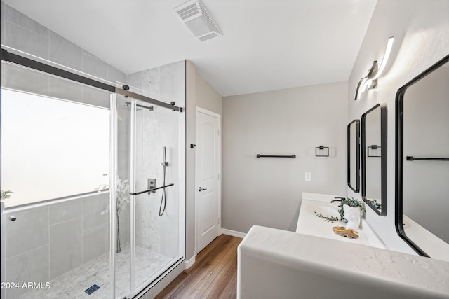 bathroom featuring a shower with shower door, vanity, wood-type flooring, and lofted ceiling