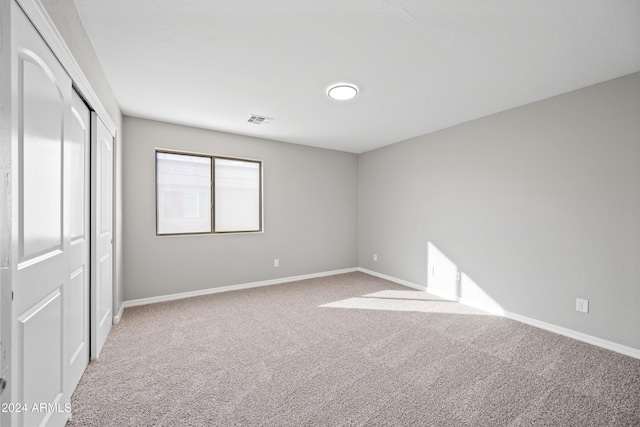 unfurnished bedroom featuring light carpet and a closet