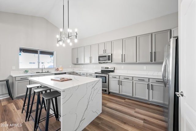 kitchen featuring light stone countertops, dark wood-type flooring, a kitchen island, and stainless steel appliances