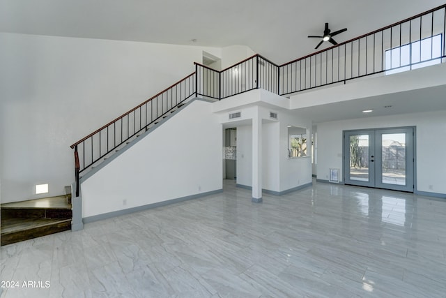 unfurnished living room with french doors, a towering ceiling, and ceiling fan