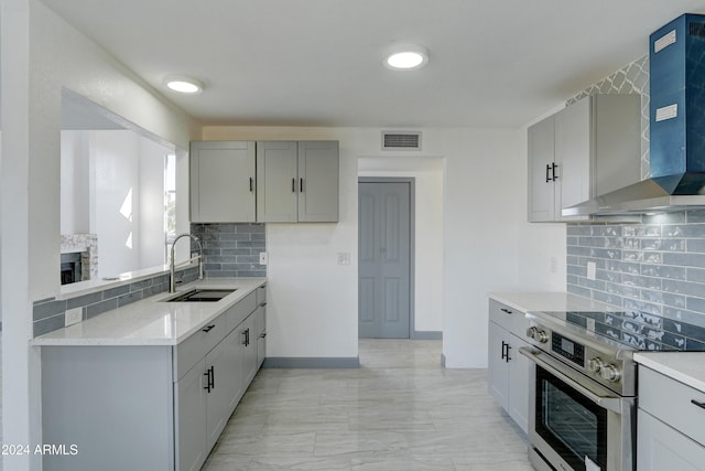 kitchen featuring gray cabinetry, sink, wall chimney exhaust hood, decorative backsplash, and high end range