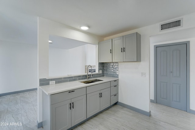 kitchen with decorative backsplash, gray cabinetry, and sink