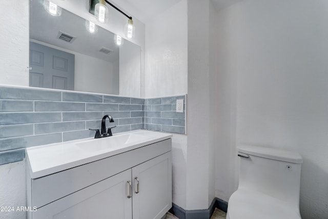 bathroom featuring vanity, tasteful backsplash, and toilet