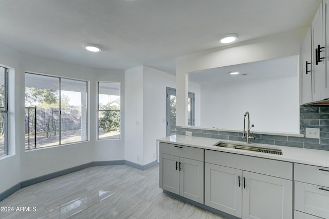 kitchen with gray cabinets, decorative backsplash, and sink