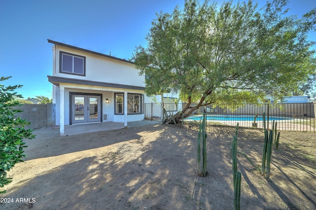 view of front of home with french doors, a patio, and a fenced in pool