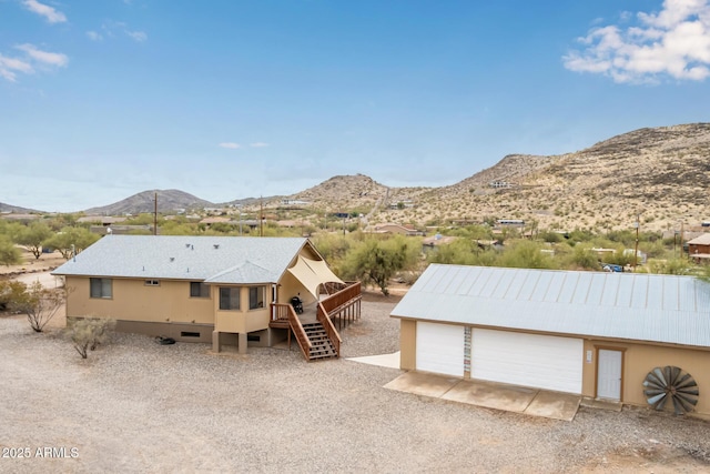 exterior space with driveway, a mountain view, stairway, an outdoor structure, and a garage