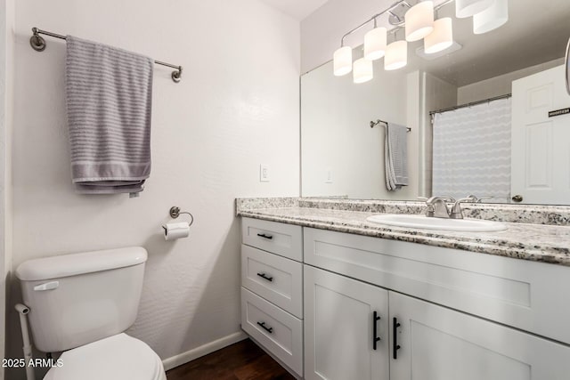 bathroom featuring baseboards, toilet, wood finished floors, and vanity