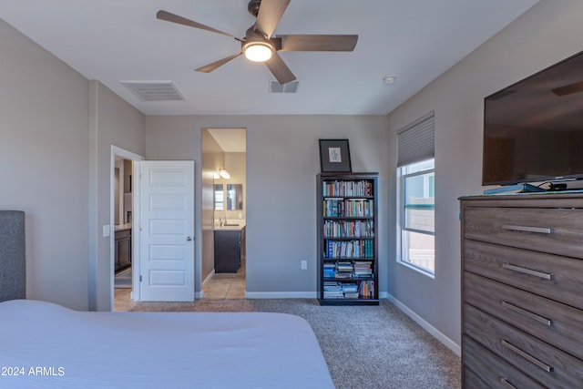 bedroom featuring ensuite bath, light colored carpet, and ceiling fan