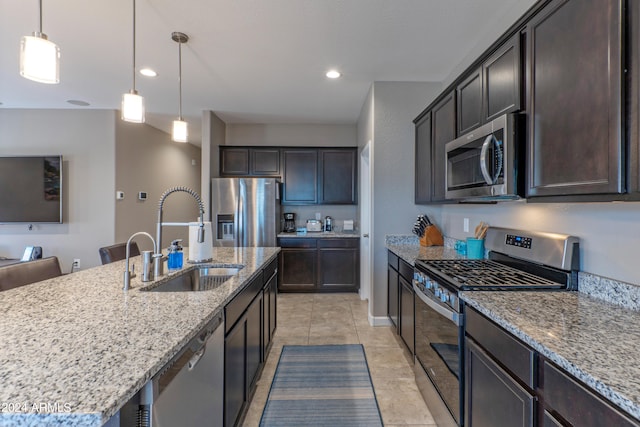 kitchen featuring stainless steel appliances, a kitchen island with sink, sink, light tile patterned flooring, and decorative light fixtures