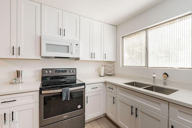 kitchen featuring white cabinetry, sink, light hardwood / wood-style flooring, and stainless steel electric range oven