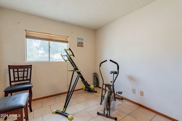 exercise room featuring light tile patterned floors and a textured ceiling