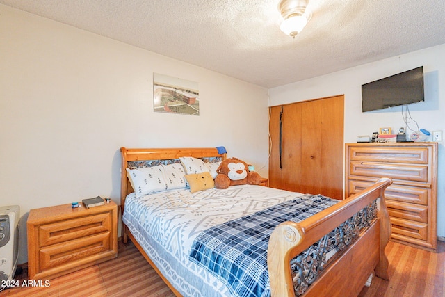 bedroom with hardwood / wood-style floors, a closet, and a textured ceiling