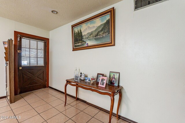 foyer entrance with light tile patterned floors and a textured ceiling