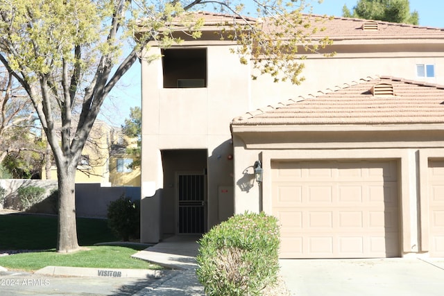 view of front facade featuring a garage, concrete driveway, a tile roof, and stucco siding