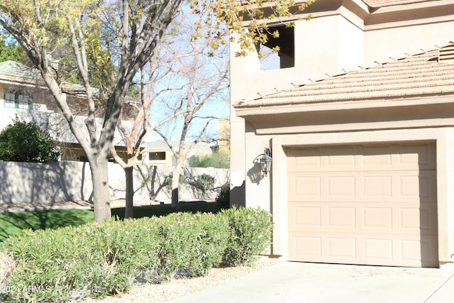 garage with fence and concrete driveway