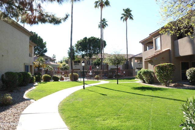 view of home's community with a residential view, fence, and a lawn