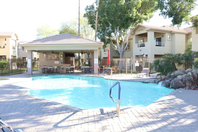 community pool featuring fence, a patio, a gazebo, and ceiling fan