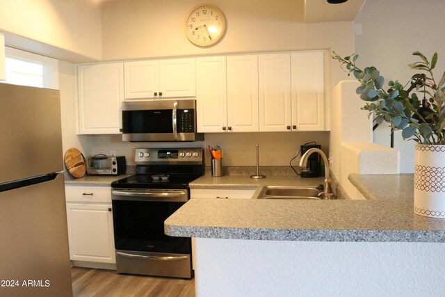 kitchen with white cabinets, light hardwood / wood-style floors, appliances with stainless steel finishes, and sink