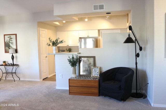 sitting room with baseboards, visible vents, and light colored carpet