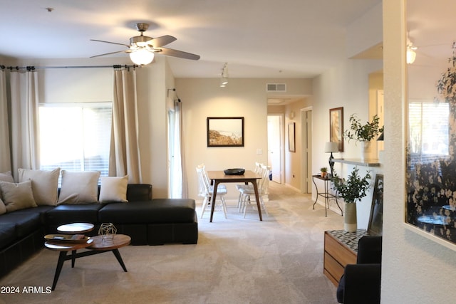 living room with ceiling fan, visible vents, and light colored carpet