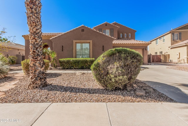 mediterranean / spanish home featuring an attached garage, a tile roof, concrete driveway, and stucco siding