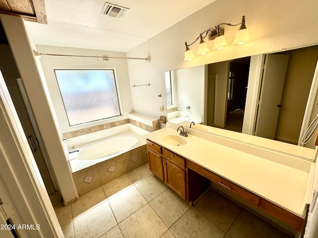 bathroom with a textured ceiling, tile patterned floors, vanity, and tiled bath