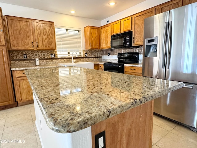 kitchen with black appliances, decorative backsplash, a center island, and sink