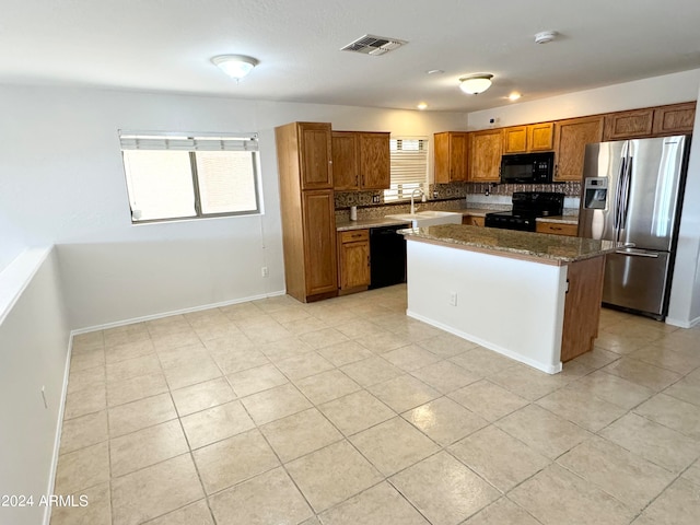 kitchen with a kitchen island, black appliances, tasteful backsplash, dark stone countertops, and sink